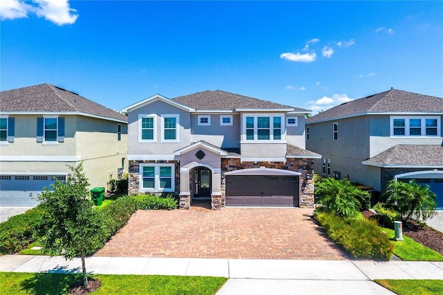 7463 Marker Ave, Kissimmee, FL 34747 - view of front facade with stucco siding, stone siding, an attached garage, and decorative driveway
