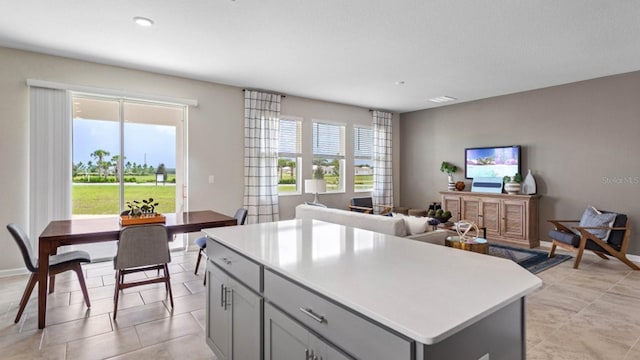 kitchen with a wealth of natural light, gray cabinets, a kitchen island, and light countertops