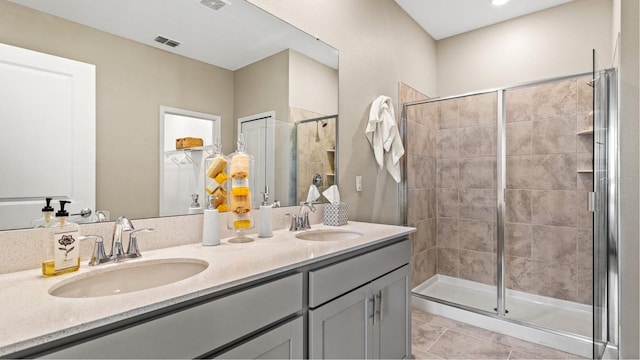 bathroom featuring a sink, visible vents, a stall shower, and double vanity