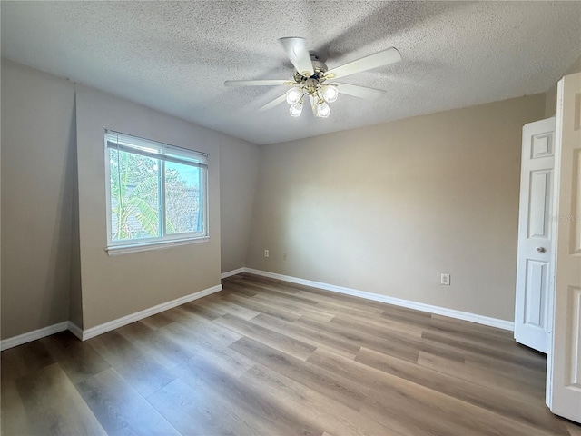 unfurnished room with a textured ceiling, wood finished floors, baseboards, and ceiling fan