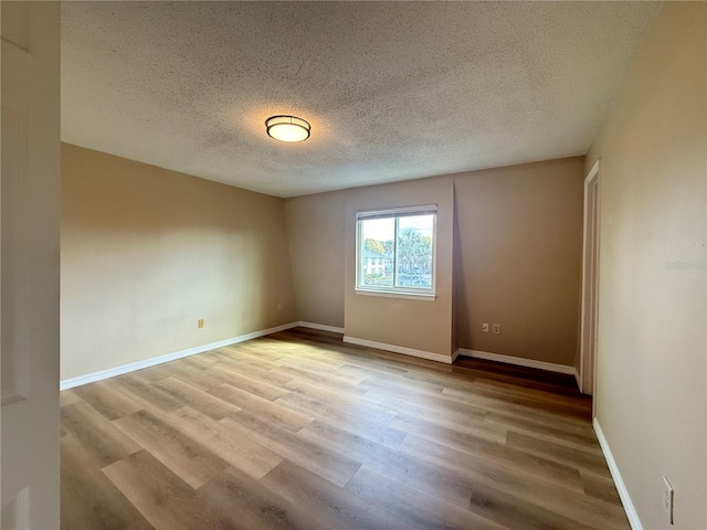 empty room featuring baseboards, a textured ceiling, and wood finished floors