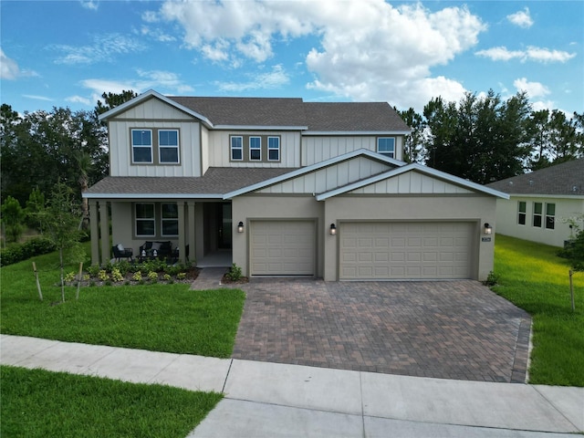 view of front facade with a garage, decorative driveway, a front lawn, and roof with shingles