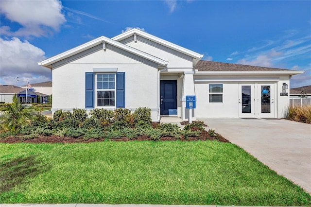 ranch-style home with a front yard, driveway, and stucco siding