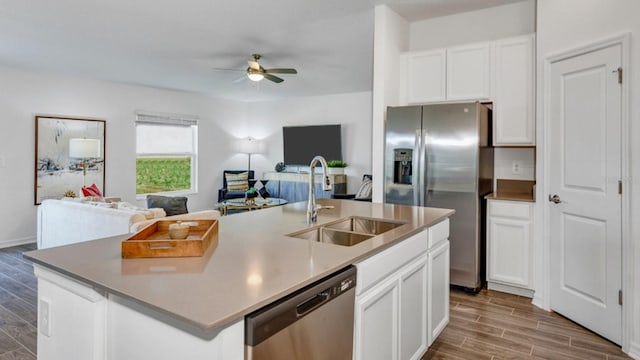 kitchen with a ceiling fan, a sink, open floor plan, appliances with stainless steel finishes, and wood tiled floor