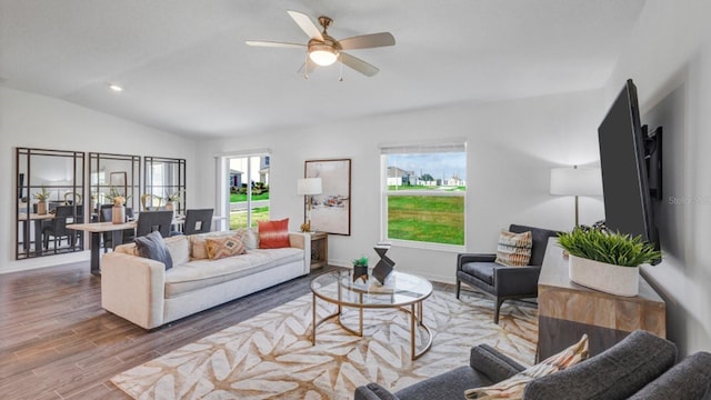 living room with baseboards, wood finished floors, a ceiling fan, and vaulted ceiling