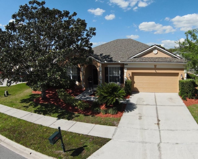 view of front facade with a front yard, an attached garage, a shingled roof, stucco siding, and concrete driveway