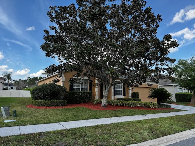 view of front of house featuring stucco siding, a front lawn, an attached garage, and fence