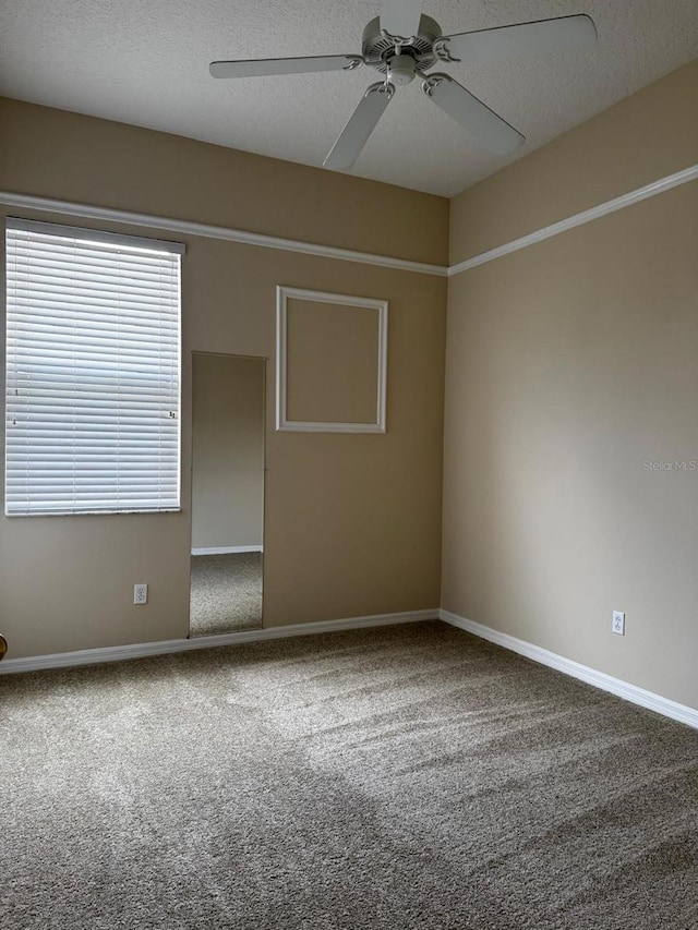 unfurnished room with baseboards, a textured ceiling, carpet, and a ceiling fan