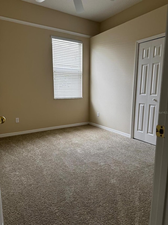 carpeted spare room with baseboards and a ceiling fan