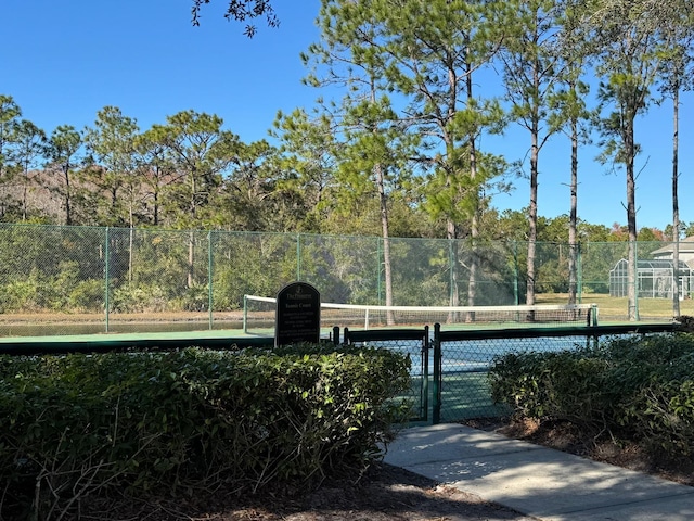 view of tennis court featuring fence and a gate