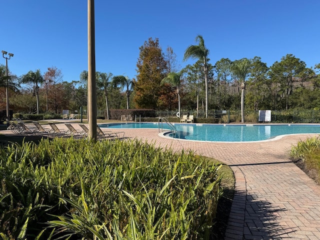 pool with a patio area and fence