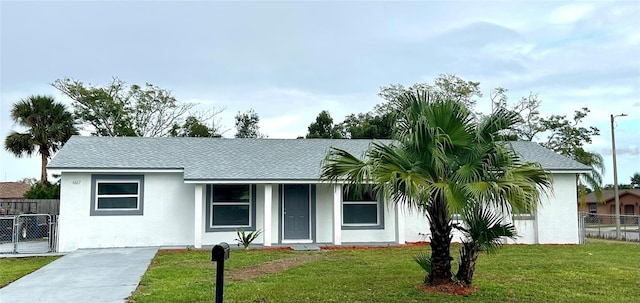 ranch-style house with stucco siding, roof with shingles, a front yard, and fence