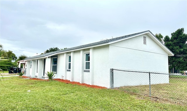 view of side of home featuring stucco siding, a yard, and fence