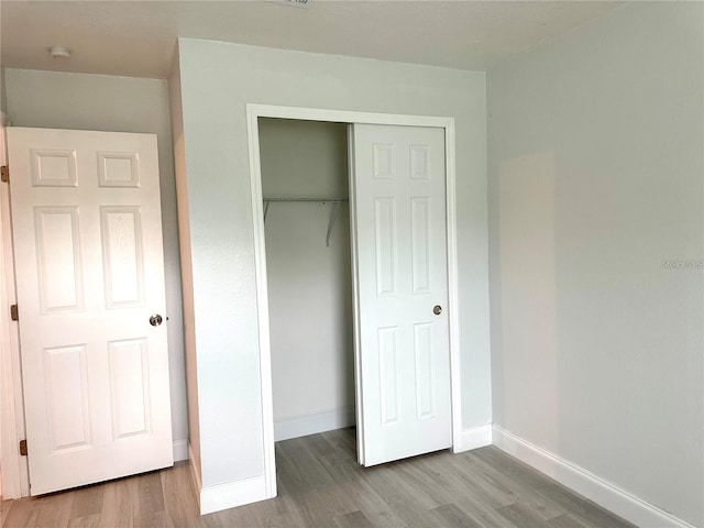 unfurnished bedroom with a closet, baseboards, and wood finished floors