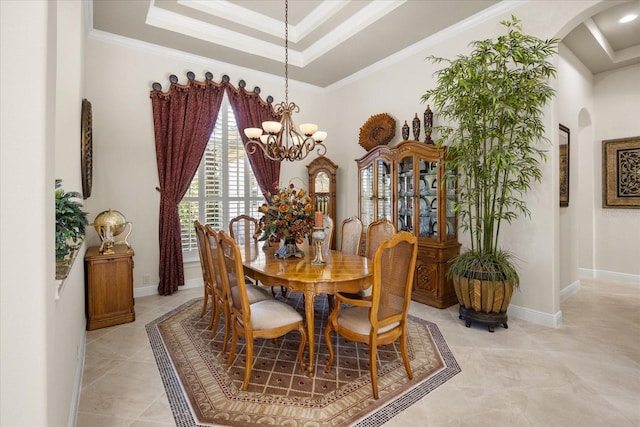 dining room featuring a raised ceiling, baseboards, arched walkways, and ornamental molding