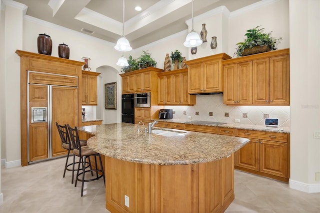 kitchen featuring a kitchen bar, black appliances, a sink, tasteful backsplash, and crown molding