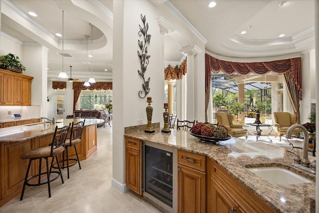 bar with a raised ceiling, wine cooler, decorative columns, and a sink