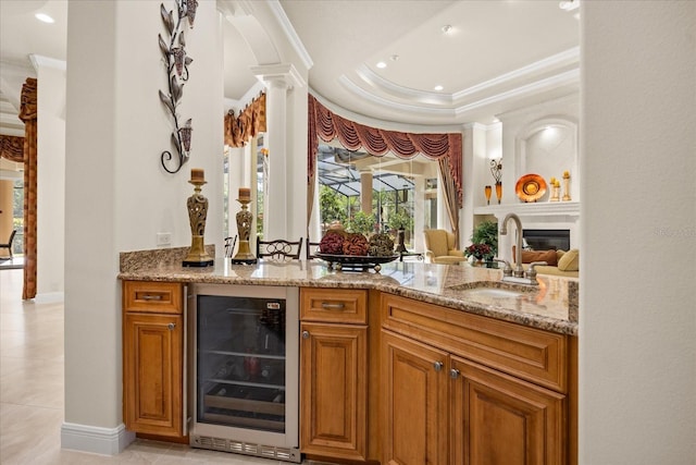 bar with beverage cooler, ornamental molding, a sink, a large fireplace, and bar