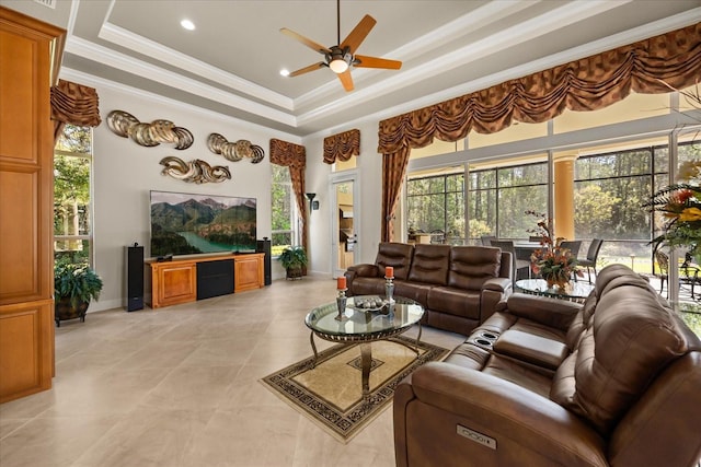 living room with a raised ceiling, plenty of natural light, crown molding, and ceiling fan