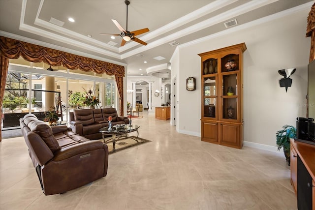 living room featuring a tray ceiling, ornamental molding, visible vents, and ceiling fan