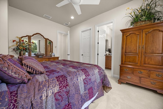 bedroom featuring light carpet, visible vents, ensuite bathroom, and a ceiling fan