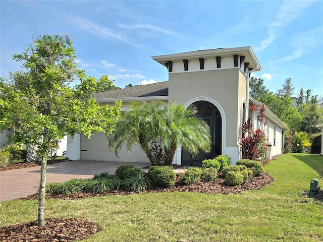 view of front of property featuring decorative driveway, a front yard, an attached garage, and stucco siding