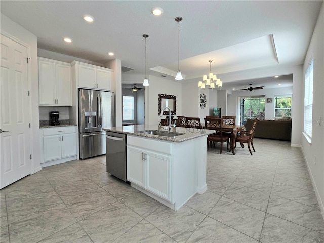 kitchen with a sink, stainless steel appliances, a raised ceiling, and ceiling fan with notable chandelier