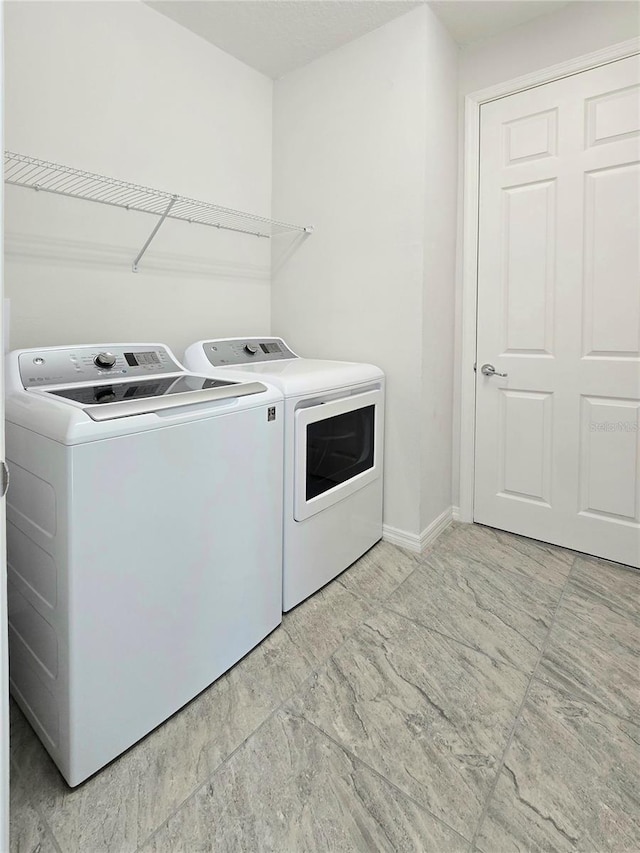 clothes washing area featuring washing machine and clothes dryer, laundry area, and baseboards