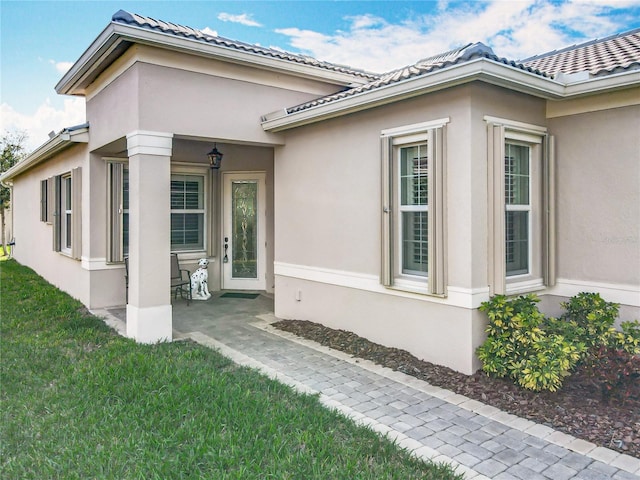 view of home's exterior featuring stucco siding, a tile roof, a lawn, and a patio