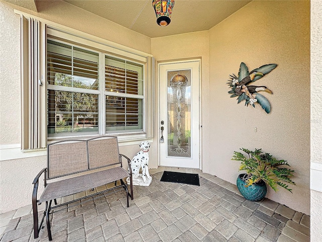 view of exterior entry featuring stucco siding and a patio