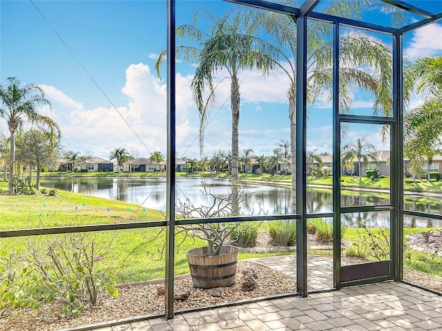 unfurnished sunroom featuring a healthy amount of sunlight, a water view, and a residential view