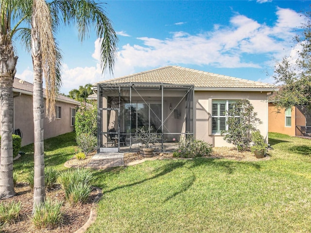 back of house featuring a lanai, a yard, a tile roof, and stucco siding