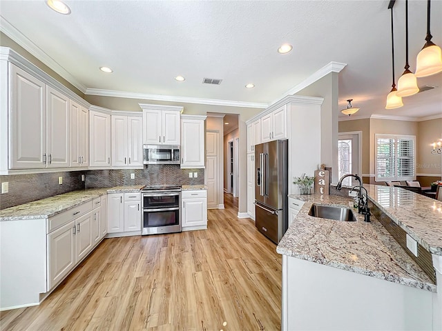 kitchen featuring visible vents, decorative backsplash, white cabinets, stainless steel appliances, and a sink