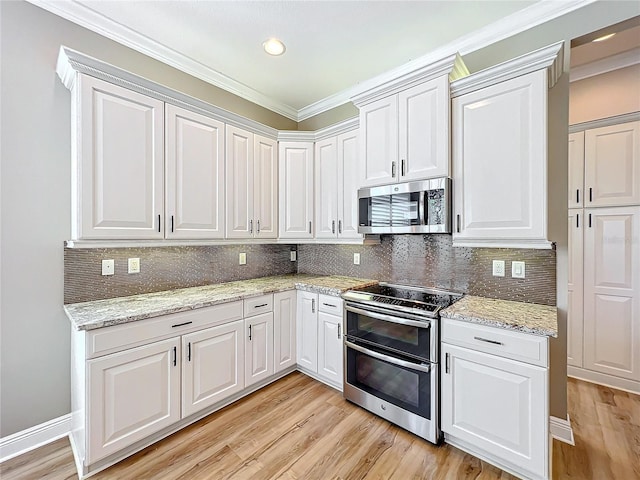 kitchen featuring decorative backsplash, white cabinets, appliances with stainless steel finishes, and light wood-style floors