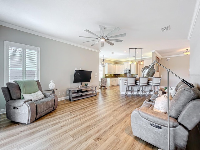 living area featuring a ceiling fan, baseboards, visible vents, light wood-style flooring, and ornamental molding