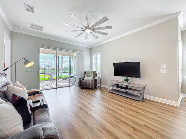 living area with ornamental molding, light wood-style floors, visible vents, and baseboards