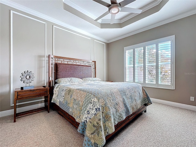 carpeted bedroom with a tray ceiling, baseboards, ceiling fan, and crown molding