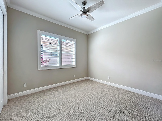 empty room featuring crown molding, light colored carpet, baseboards, and ceiling fan