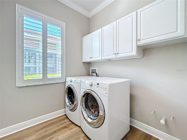 clothes washing area featuring baseboards, washing machine and clothes dryer, light wood-style flooring, cabinet space, and crown molding