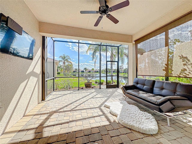 sunroom featuring ceiling fan and a water view