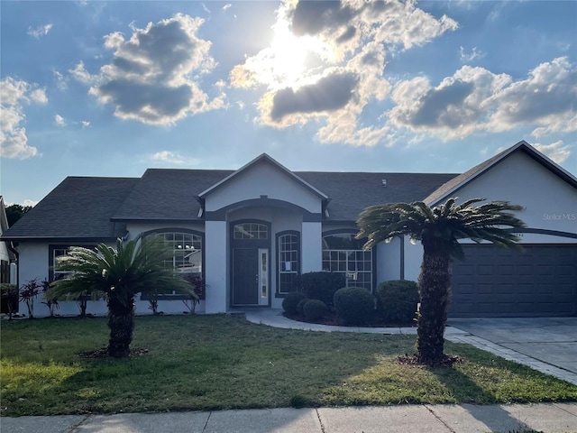 ranch-style home with stucco siding, driveway, an attached garage, and a front lawn