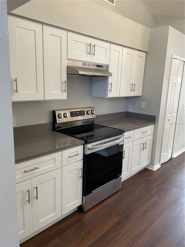 kitchen with under cabinet range hood, stainless steel electric stove, dark countertops, and white cabinets