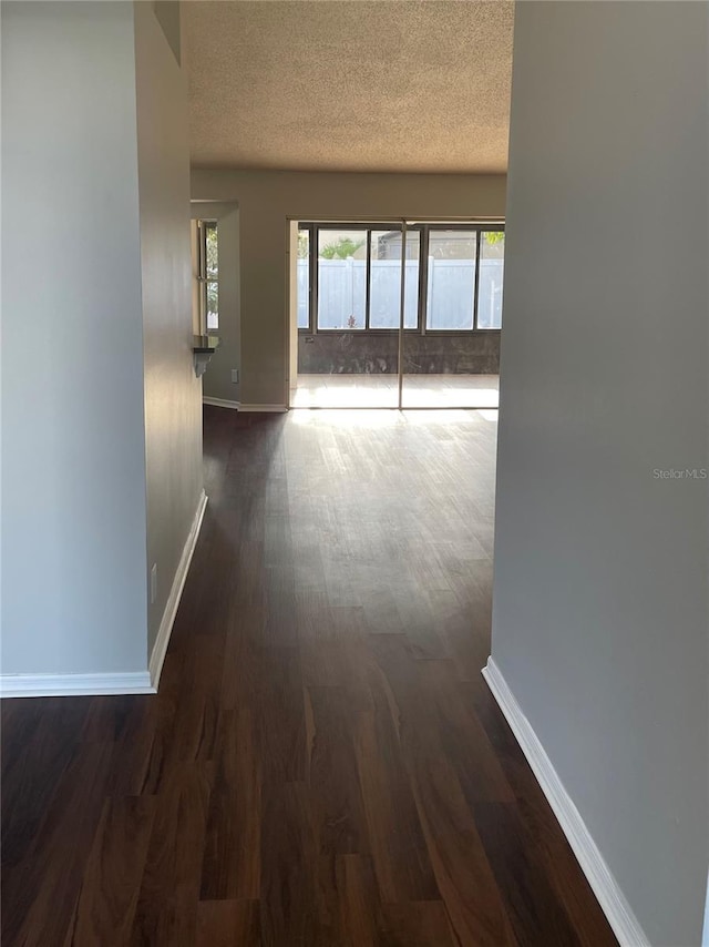 hall with baseboards, a textured ceiling, and dark wood-style floors