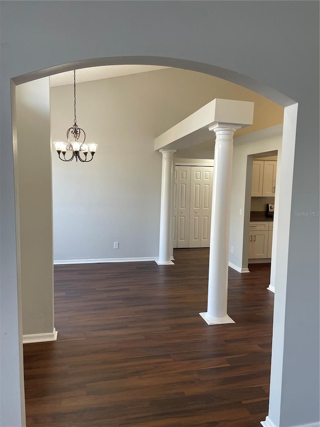 interior space featuring an inviting chandelier, dark wood-type flooring, arched walkways, and baseboards