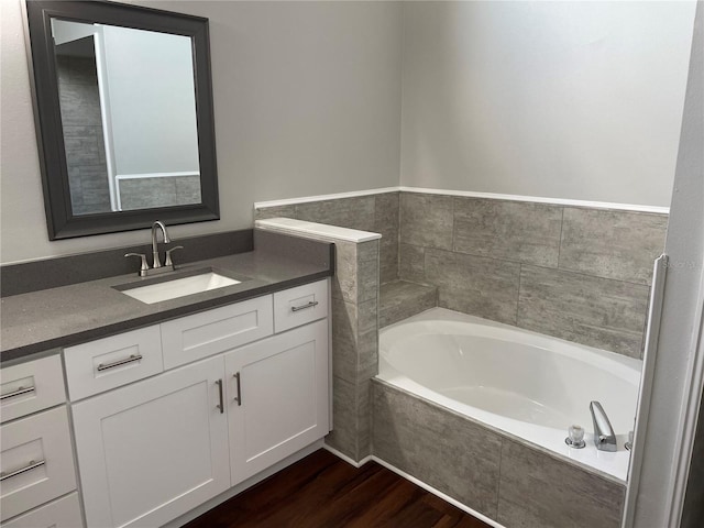 bathroom featuring a garden tub, wood finished floors, and vanity