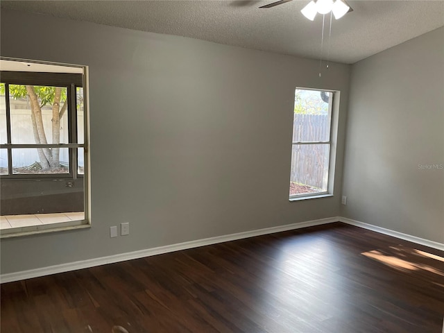 unfurnished room with a textured ceiling, baseboards, dark wood-type flooring, and a ceiling fan