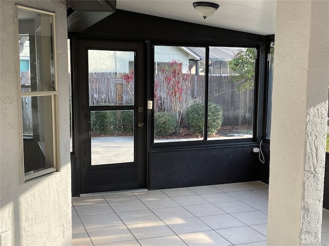 doorway to outside with tile patterned flooring, plenty of natural light, and a textured wall