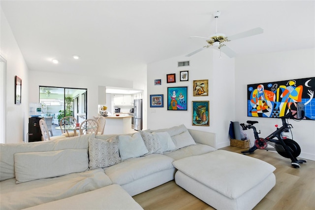 living room featuring visible vents, baseboards, light wood-type flooring, lofted ceiling, and a ceiling fan