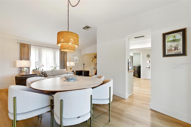 dining space with visible vents, baseboards, a notable chandelier, and light wood-style flooring