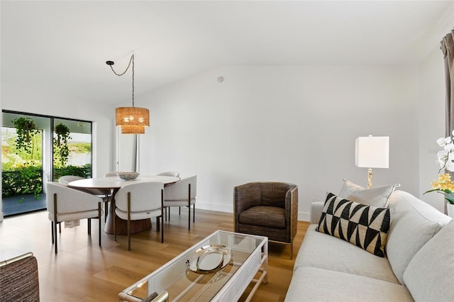 living area with light wood-type flooring, baseboards, and vaulted ceiling